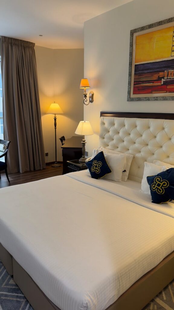 Cozy hotel room featuring a plush bed, artistic decor, warm lighting, and stylish furnishings.