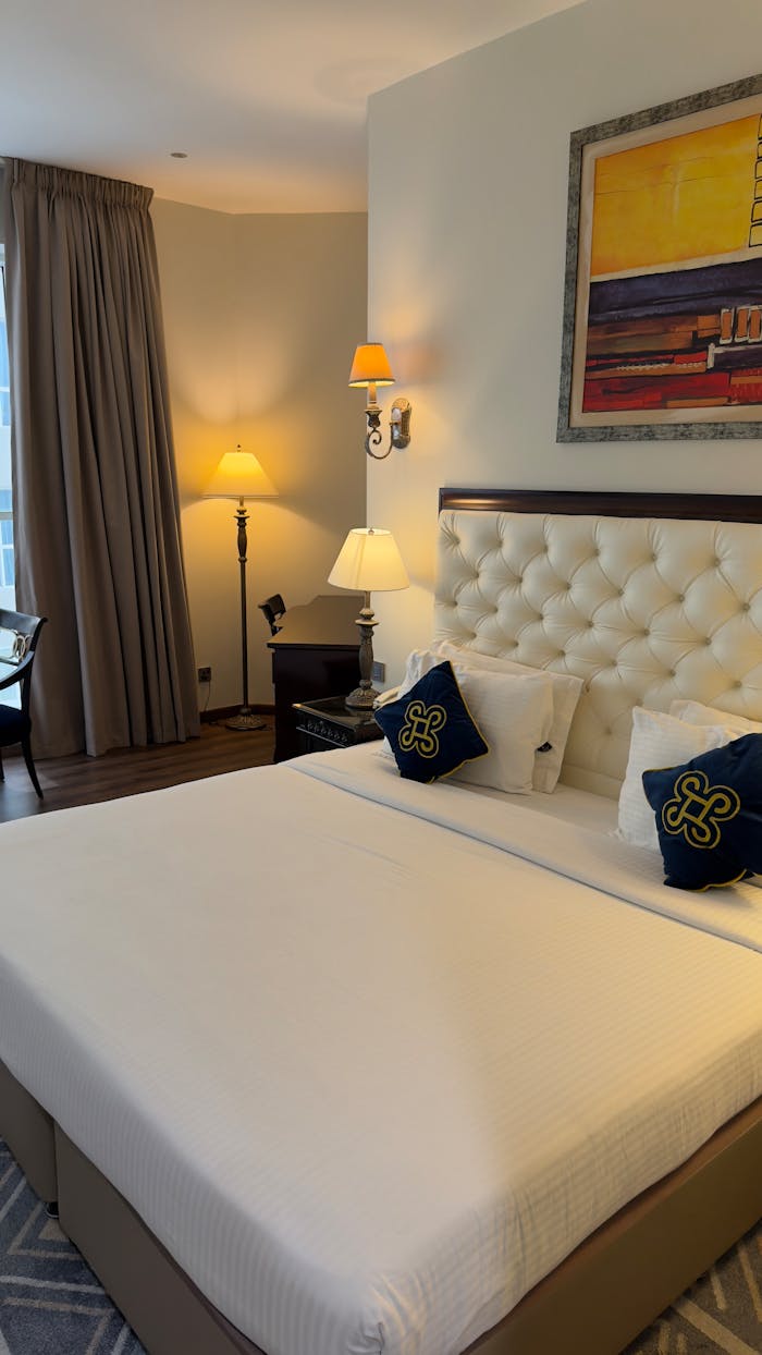 Cozy hotel room featuring a plush bed, artistic decor, warm lighting, and stylish furnishings.